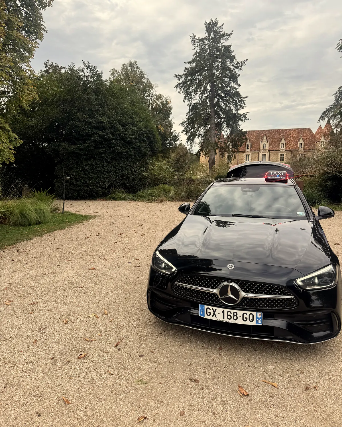 Le taxi de Michaël garé dans une cour arborée, lumineux taxi La Rochefoucauld sur le toit